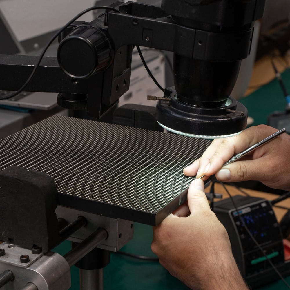 A technician performs a pixel repair on an LED module.